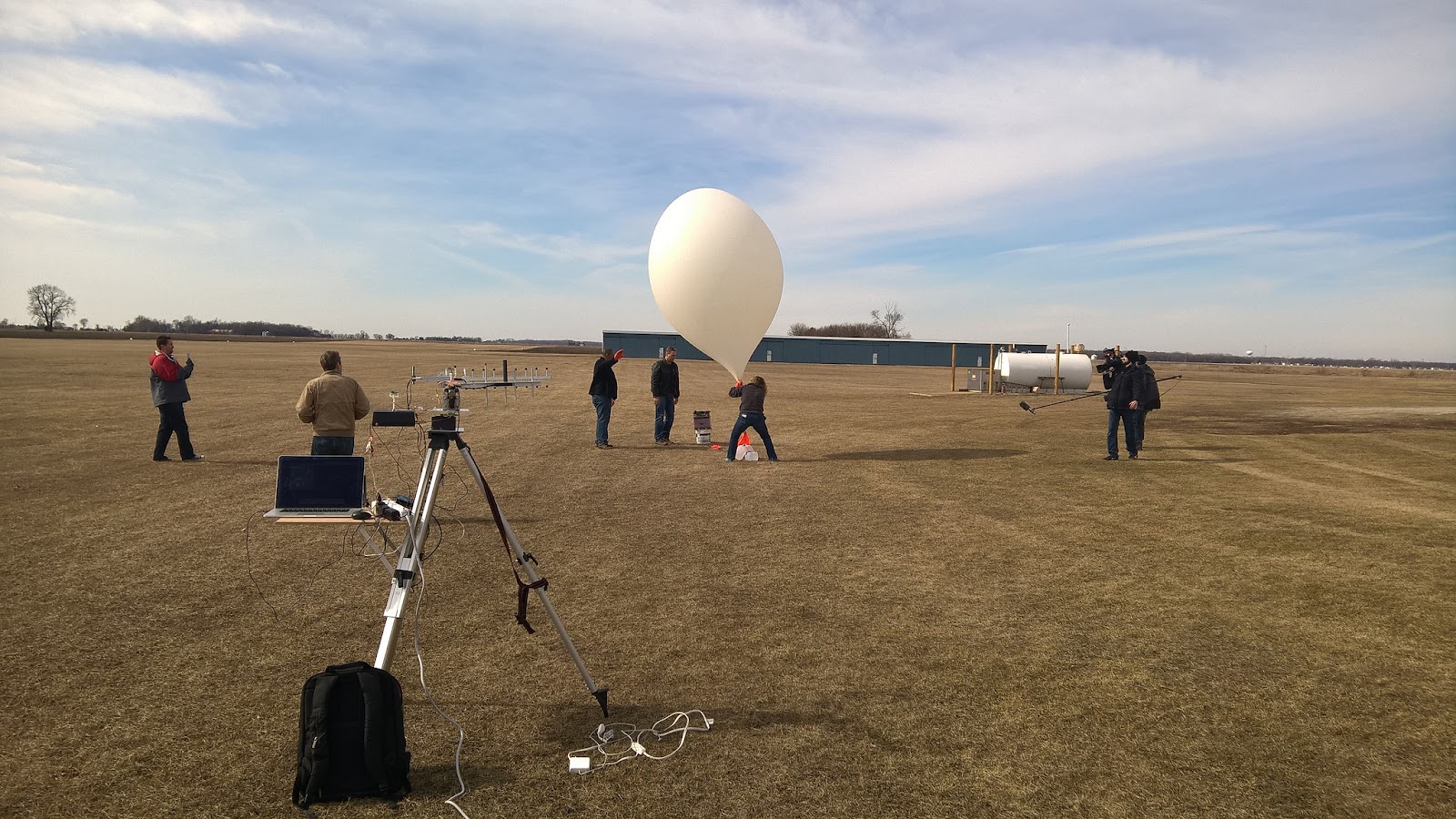 several people in field holding a growing balloon